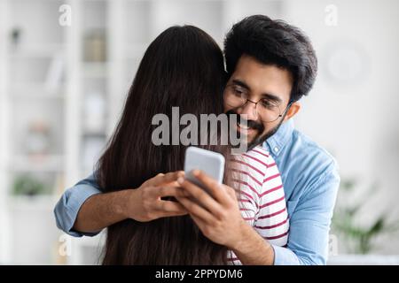 Ein fröhlicher indianer, der sich unterhält, während er seine Freundin umarmt Stockfoto