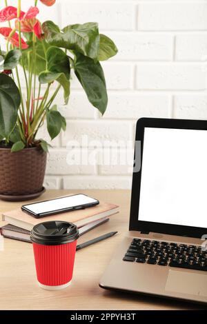 Laptop-Computer, weißer, leerer Bildschirm und Smartphone auf Holztisch. Vertikales foto. Draufsicht. Stockfoto