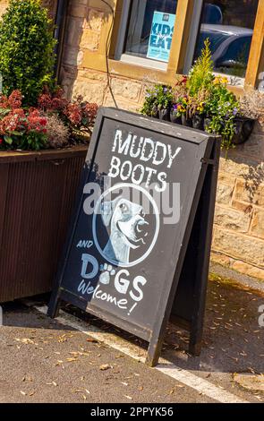 Schlammstiefel und Hunde Willkommensschild auf einer Tafel vor einem britischen Pub, in dem Wanderer willkommen sind. Stockfoto