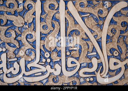 Details der Stuckdekoration mit arabischen Schriften in Blau an den Palastwänden im Alhambra-Komplex in Granada, Andalusien, Spanien. Stockfoto