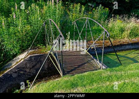 Die rostende einspaltige Fußgängerbrücke aus Gusseisen überquert die Schleusentore am Loch 8 des Letham Grange Golfplatzes ClubÕs Old Course. Stockfoto