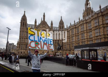 Extinction Rebellion Protest, Freitag, den 21. April 2023. Der Aktivist hält vor dem Palast von Westminster ein großes Schild mit der Aufschrift „Stop Climate Crime“. XR London. Stockfoto