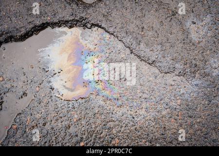 Benzinflecken auf Asphalt. Benzin ist auf der Straße verschüttet. Straße in den Gruben. Stockfoto