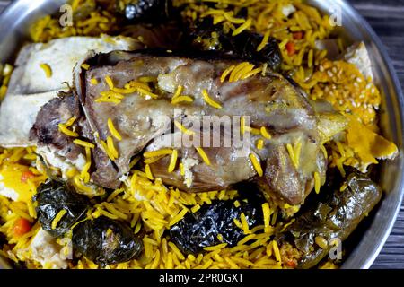 Ein gut gekochter Lammschaft mit gelbem Basmati-Reis und gemischtem Gemüse und gefüllten Traubenblättern Mahshi Mahshy mit weißem Reis, der im OV geröstet wird Stockfoto