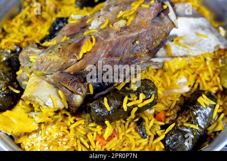 Ein gut gekochter Lammschaft mit gelbem Basmati-Reis und gemischtem Gemüse und gefüllten Traubenblättern Mahshi Mahshy mit weißem Reis, der im OV geröstet wird Stockfoto