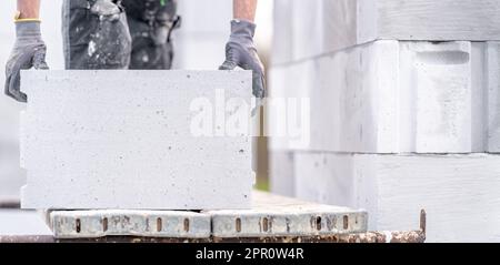 Ein Mauerwerk baut die Wand eines Hauses aus Betonziegeln Stockfoto
