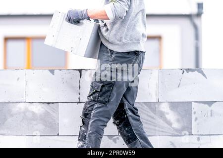 Ein Mauerwerk baut die Wand eines Hauses aus Betonziegeln Stockfoto