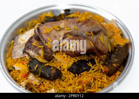 Ein gut gekochter Lammschaft mit gelbem Basmati-Reis und gemischtem Gemüse und gefüllten Traubenblättern Mahshi Mahshy mit weißem Reis, der im OV geröstet wird Stockfoto