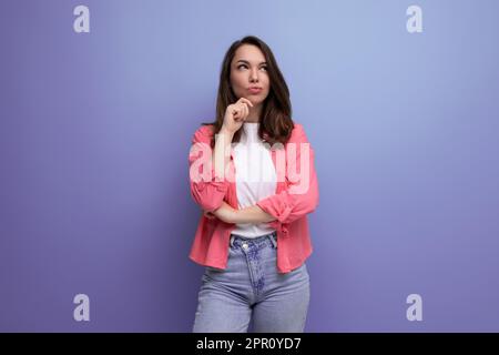 Pensive, traumhafte, europäische Brünette 30s Frau in pinkfarbenem Hemd mit Studiohintergrund und Kopierbereich Stockfoto