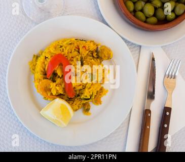 Paella mit Garnelen, Pfeffer, Gemüse und Zitrone auf Platte Stockfoto