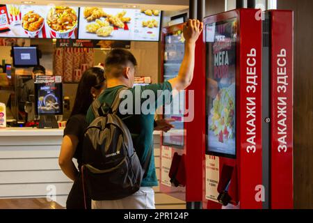 Moskau, Russland. 25. April 2023. Die Leute bestellen in einem KFC-Restaurant in Moskau. Das erste Restaurant unter der neuen Marke Rostic's eröffnete in Moskau an dem Ort, an dem KFC zuvor den Betrieb in Russland eingestellt hatte. Im Juli 2022 berichteten die Medien, dass Yum! Brands, Eigentümer von KFC und Pizza Hut in Russland, stellte seine Aktivitäten im Land ein und übertrug das Eigentum an einen lokalen Betreiber. Vor kurzem wurde bekannt gegeben, dass die ehemaligen KFC-Betriebe in Russland nun unter der Marke Rostic operieren werden. Kredit: SOPA Images Limited/Alamy Live News Stockfoto