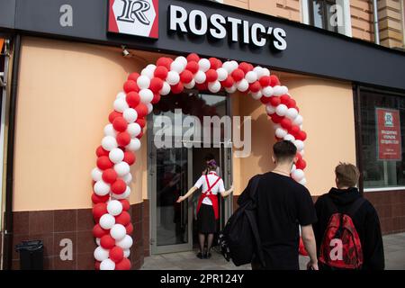 Moskau, Russland. 25. April 2023. Leute betreten ein neues Restaurant von Rostic. Das erste Restaurant unter der neuen Marke Rostic's eröffnete in Moskau an dem Ort, an dem KFC zuvor den Betrieb in Russland eingestellt hatte. Im Juli 2022 berichteten die Medien, dass Yum! Brands, Eigentümer von KFC und Pizza Hut in Russland, stellte seine Aktivitäten im Land ein und übertrug das Eigentum an einen lokalen Betreiber. Vor kurzem wurde bekannt gegeben, dass die ehemaligen KFC-Betriebe in Russland nun unter der Marke Rostic operieren werden. Kredit: SOPA Images Limited/Alamy Live News Stockfoto