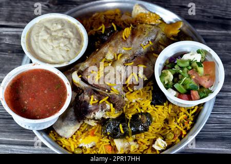 Ein gut gekochter Lammschaft mit gelbem Basmati-Reis und gemischtem Gemüse und gefüllten Traubenblättern Mahshi Mahshy mit weißem Reis, der im OV geröstet wird Stockfoto