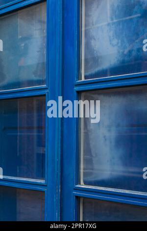 Blaue Doppeltür aus Holz mit Glasfenstern und geschlossenen Fensterläden Stockfoto