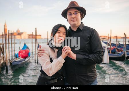 Ein gemischtes Paar von Liebhabern umarmt Venedig vor den Gondeln Stockfoto