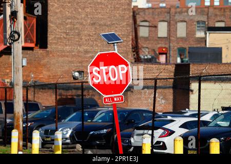 Ein solarbetriebenes blinkendes LED-Stoppschild. Diese solarbetriebenen Schilder werden während der Abendstunden beleuchtet, um den Fahrer auf das Schild aufmerksam zu machen. Stockfoto