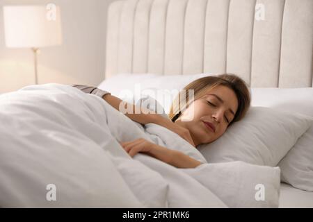 Frau unter warmweißer Decke, die im Bett schläft Stockfoto