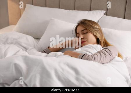 Frau unter warmweißer Decke, die im Bett schläft Stockfoto