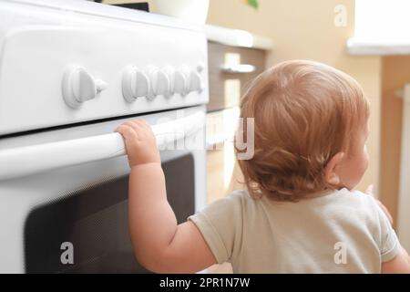 Kleines Kind, das drinnen mit Gasherd spielt. Gefahren in der Küche Stockfoto