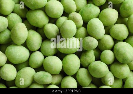 Leckere Wasabi-beschichtete Erdnüsse als Hintergrund, Draufsicht Stockfoto