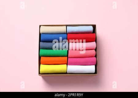 Box mit verschiedenen bunten Socken auf hellrosa Hintergrund, Draufsicht Stockfoto