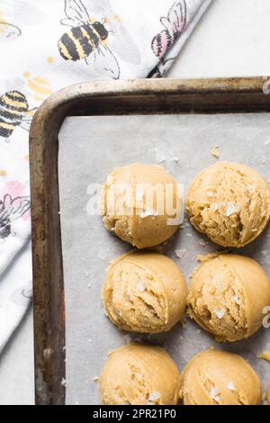 Schaufeln mit Vanille-Keksteig auf einem mit Pergament ausgekleideten Keksblatt, einfacher Vanille-Keksteig, der gleich gebacken wird Stockfoto