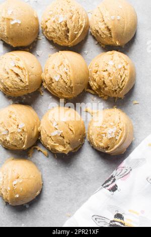 Schaufeln mit Vanille-Keksteig auf einem mit Pergament ausgekleideten Keksblatt, einfacher Vanille-Keksteig, der gleich gebacken wird Stockfoto
