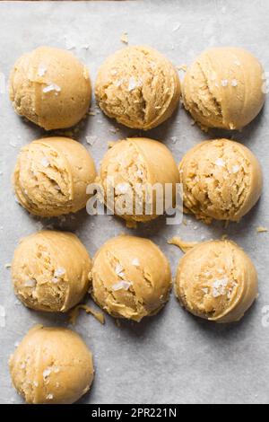 Schaufeln mit Vanille-Keksteig auf einem mit Pergament ausgekleideten Keksblatt, einfacher Vanille-Keksteig, der gleich gebacken wird Stockfoto