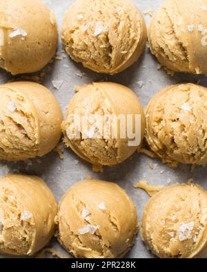 Schaufeln mit Vanille-Keksteig auf einem mit Pergament ausgekleideten Keksblatt, einfacher Vanille-Keksteig, der gleich gebacken wird Stockfoto