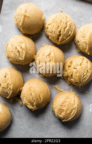 Schaufeln mit Vanille-Keksteig auf einem mit Pergament ausgekleideten Keksblatt, einfacher Vanille-Keksteig, der gleich gebacken wird Stockfoto