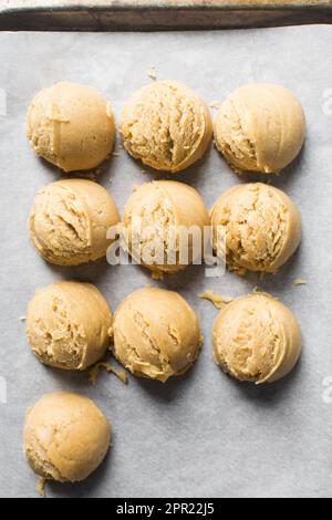 Schaufeln mit Vanille-Keksteig auf einem mit Pergament ausgekleideten Keksblatt, einfacher Vanille-Keksteig, der gleich gebacken wird Stockfoto