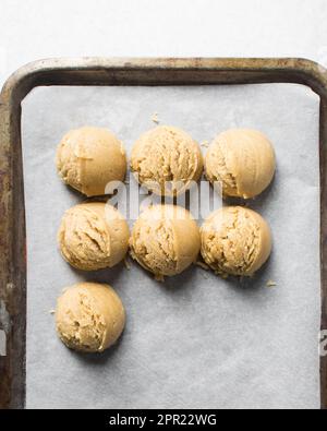 Schaufeln mit Vanille-Keksteig auf einem mit Pergament ausgekleideten Keksblatt, einfacher Vanille-Keksteig, der gleich gebacken wird Stockfoto