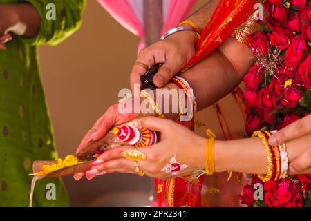 Hindu-bengalisch-Hochzeitsrituale, wenn Braut und Bräutigam Gangajal auf heiliges Feuer gießen. Die Hände der Braut und des Bräutigams, wie sie in traditionell gesehen werden Stockfoto