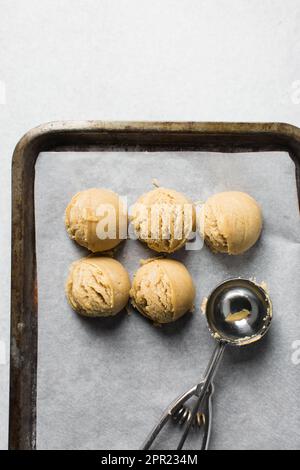 Schaufeln mit Vanille-Keksteig auf einem mit Pergament ausgekleideten Keksblatt, einfacher Vanille-Keksteig, der gleich gebacken wird Stockfoto