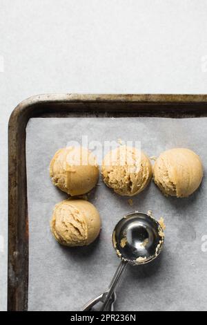 Schaufeln mit Vanille-Keksteig auf einem mit Pergament ausgekleideten Keksblatt, einfacher Vanille-Keksteig, der gleich gebacken wird Stockfoto