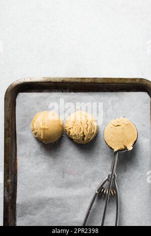Schaufeln mit Vanille-Keksteig auf einem mit Pergament ausgekleideten Keksblatt, einfacher Vanille-Keksteig, der gleich gebacken wird Stockfoto