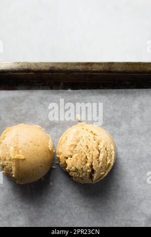 Schaufeln mit Vanille-Keksteig auf einem mit Pergament ausgekleideten Keksblatt, einfacher Vanille-Keksteig, der gleich gebacken wird Stockfoto