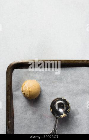 Schaufeln mit Vanille-Keksteig auf einem mit Pergament ausgekleideten Keksblatt, einfacher Vanille-Keksteig, der gleich gebacken wird Stockfoto