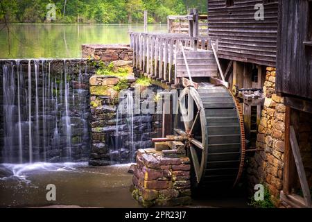 Der Historic Yates Mill County Park in Raleigh, North Carolina, bietet einen schönen Blick auf den Mühlenteich, den Wasserfall, die Wasserrutsche und das Wasserrad. Stockfoto