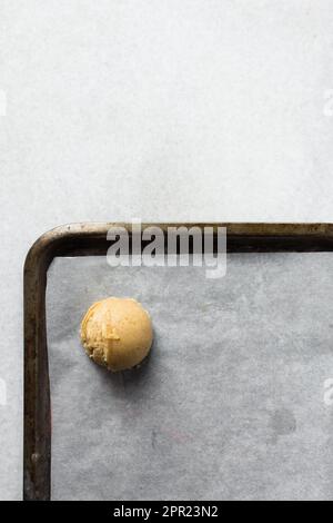 Schaufeln mit Vanille-Keksteig auf einem mit Pergament ausgekleideten Keksblatt, einfacher Vanille-Keksteig, der gleich gebacken wird Stockfoto