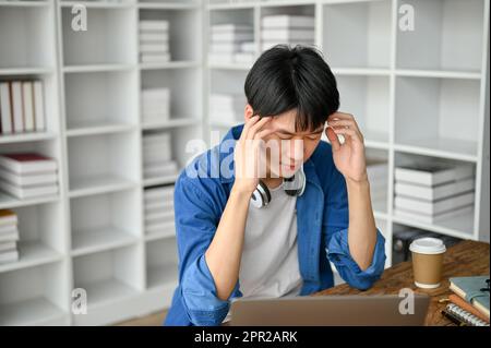 Stressiger junger Student, der sich nach einem langen Studium müde fühlt. Bildungskonzept Stockfoto