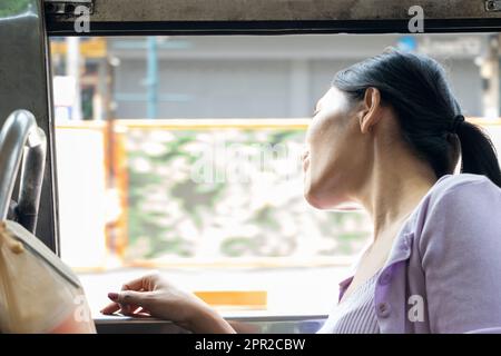Eine junge Frau schaut aus dem Fenster eines fahrenden Busses Stockfoto