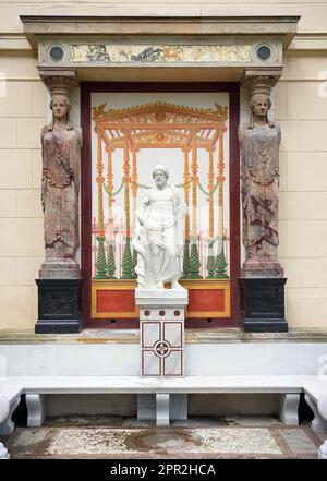 Berlin, Deutschland. 24. April 2023. Die Marmorskulptur des griechischen gottes des heilenden Asklepios befindet sich wieder an der Ostfassade des Casinos im Glienicke Palace Park zwischen zwei Kariatiden (Skulpturen von Frauen anstelle einer Säule) und wird von zwei Restauratoren repariert. Mit der Restaurierung der Skulptur, antiker Säulenteile und eines Wandbildes konnte die Stiftung Preußische Paläste und Gärten Berlin-Brandenburg (SPSG) die Restaurierung des Bank-Ensembles im Kasino in den Gärten des Schlosses Glienicke abschließen. Kredit: Soeren Stache/dpa/Alamy Live News Stockfoto