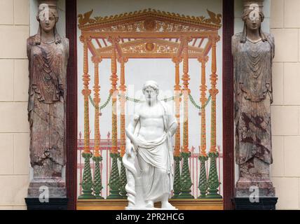 Berlin, Deutschland. 24. April 2023. Die Marmorskulptur des griechischen gottes des heilenden Asklepios befindet sich wieder an der Ostfassade des Casinos im Glienicke Palace Park zwischen zwei Kariatiden (Skulpturen von Frauen anstelle einer Säule) und wird von zwei Restauratoren repariert. Mit der Restaurierung der Skulptur, antiker Säulenteile und eines Wandbildes konnte die Stiftung Preußische Paläste und Gärten Berlin-Brandenburg (SPSG) die Restaurierung des Bank-Ensembles im Kasino in den Gärten des Schlosses Glienicke abschließen. Kredit: Soeren Stache/dpa/Alamy Live News Stockfoto