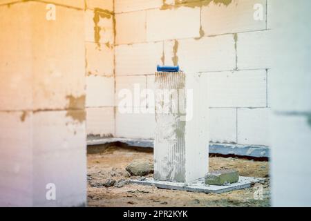 In einem unvollendeten Gebäude befindet sich ein großer Porenbeton. Der Gasblock ist durch die Tür eines frisch gebauten Hauses sichtbar. Säge zum Schneiden Stockfoto