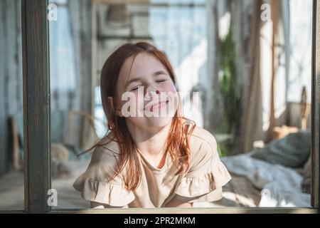 Komisches Mädchen, das rummacht und ihre Nase gegen das Glas drückt Stockfoto