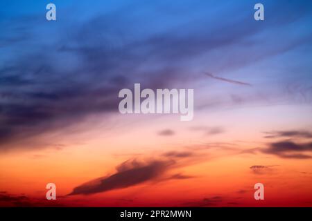 Sonnenuntergang am Himmel mit rotem Licht der untergehenden Sonne. Abendwolken im orangefarbenen Licht der Sonnenuntergangsstrahlen Stockfoto