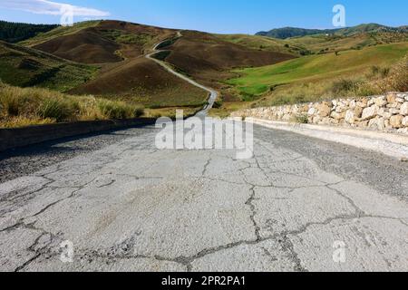 Unbefestigte Straße durch Hügel von rotem Land in Sizilien, Italien Stockfoto