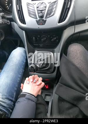 Mann und Frau, Mädchen, verliebtes Paar, Händchen halten mit ansehnlichen Händen in einem Auto mit mechanischem 6-Gang-Getriebe. Stockfoto