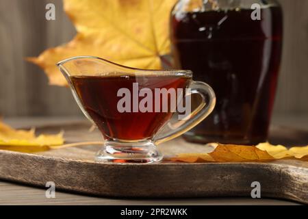 Saucen und eine Flasche leckeren Ahornsirup auf einem Holztisch, Nahaufnahme Stockfoto